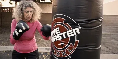 Senior woman boxing bag training at HB Fight Club Huntington Beach CA